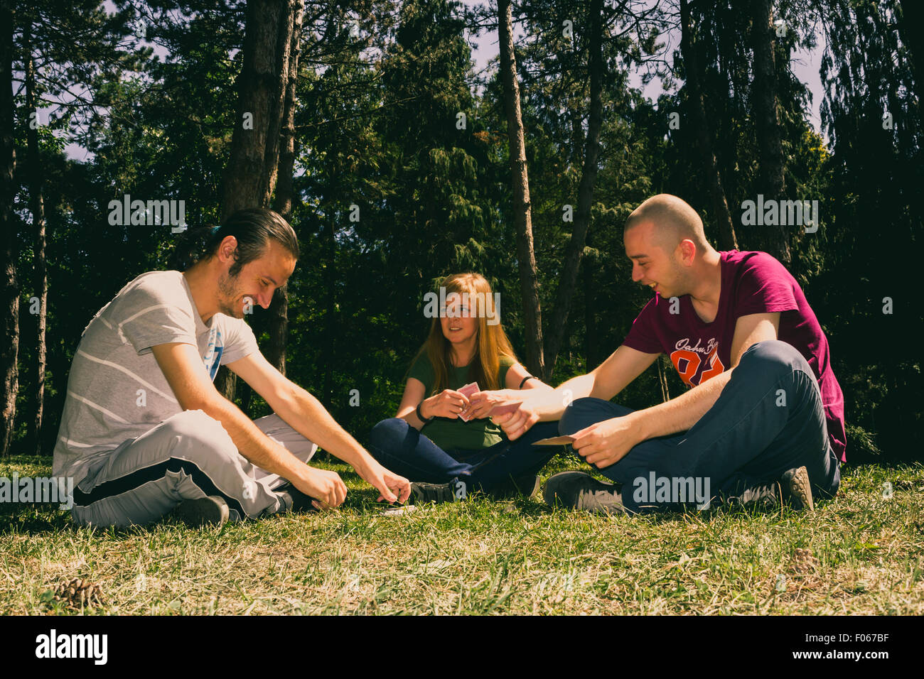 Drei Freunde, die Spaß von Spielkarten im Wald Stockfoto