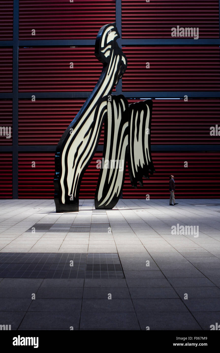 Ein Mann geht durch die Skulptur Pinselstrich von Roy Lichtenstein im Gericht von Reina Sofia Museum in Madrid, Spanien. Stockfoto