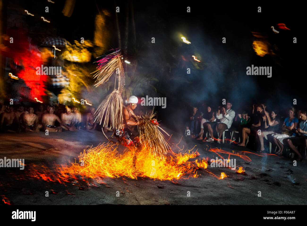 Ein Feuertanz-Darsteller läuft über einen Haufen brennender Kokosnüsse vor Touristen, während der Kecak- und Feuertanz-Show in Ubud, Gianyar, Bali, Indonesien. Stockfoto