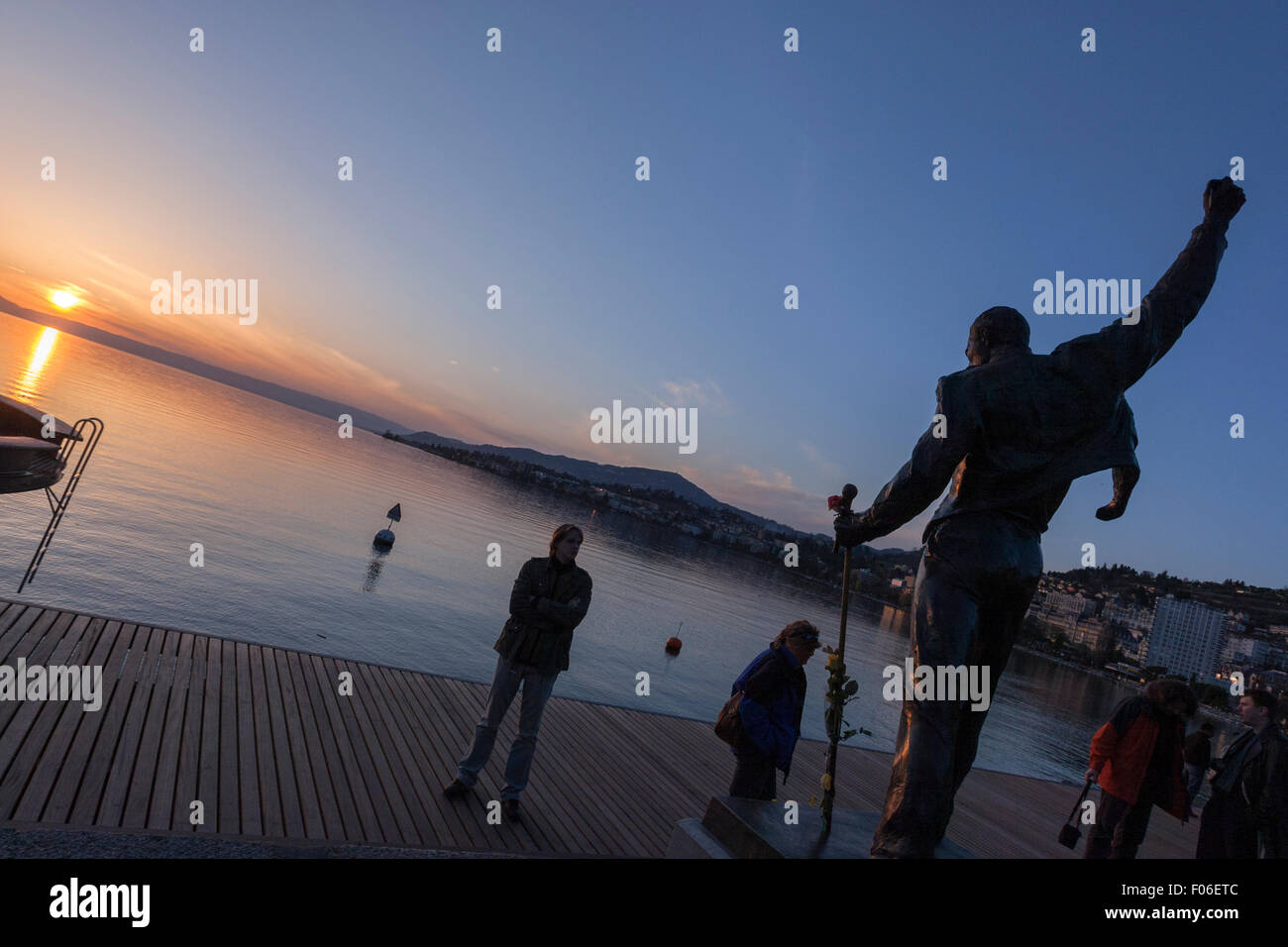 Touristen, die Freddie Mercury Statue des Künstlers Irena Sedlecka, am Marktplatz mit Blick auf den Genfer See bei Sonnenuntergang zu beobachten. Montreux Stockfoto