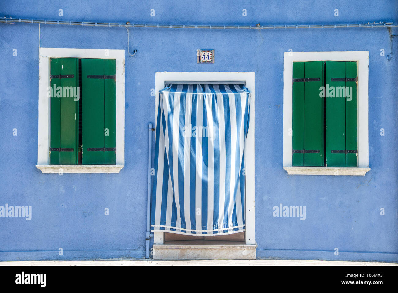 Grünen Fensterläden und blauen Streifen Vorhang aus einem bunten Haus der Insel Burano, Venedig, Italien Stockfoto