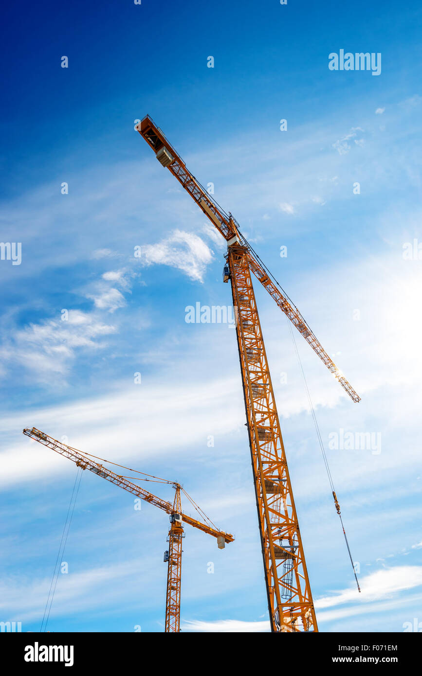 Zwei Industriekrane in Aktion auf der Baustelle gegen blauen Himmel Stockfoto