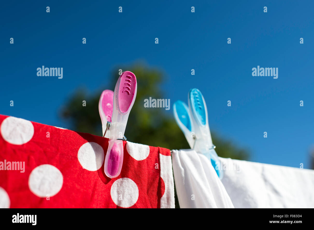 Rote und weiße Wäsche trocknen in der Sonne auf der Wäscheleine mit farbigen Stöpsel gekoppelt. Stockfoto