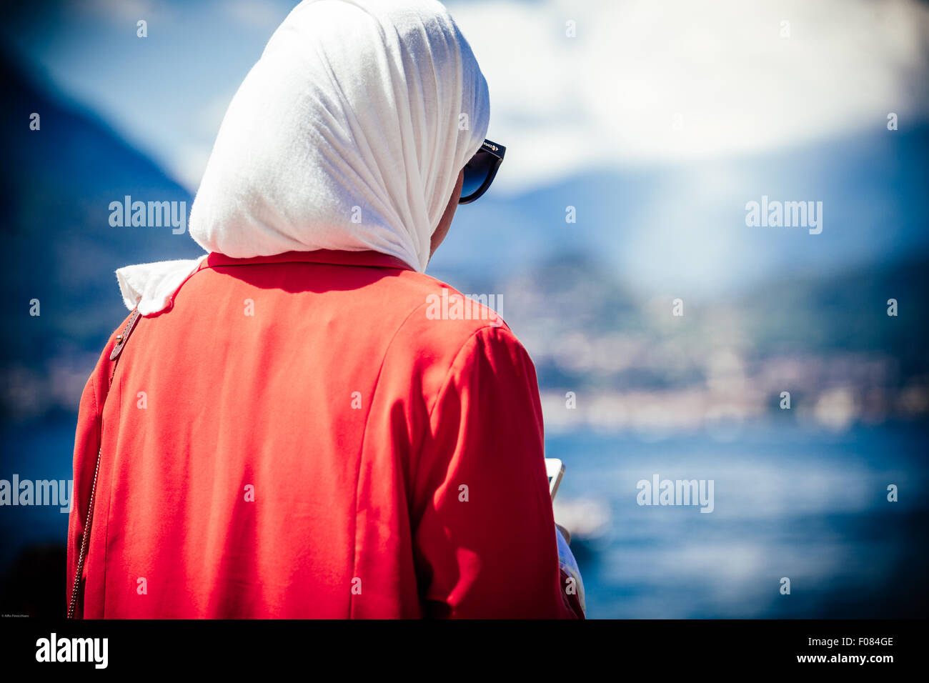 Muslimische Frau, während sie ihr Smartphone, im Hintergrund der See von Garda, Italien Stockfoto