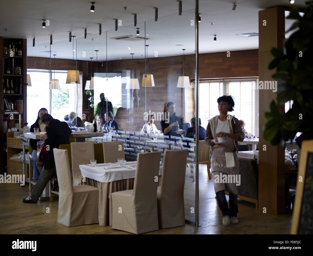 Menschen Essen im Restaurant Terrassa und Glas Trennwand mit Hängelampen Stockfoto
