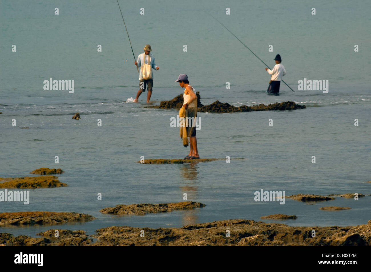 Männer, die auf flachem Wasser spazieren, um am Strand von Carita in Pandeglang, Banten, Indonesien, zu fischen. Stockfoto