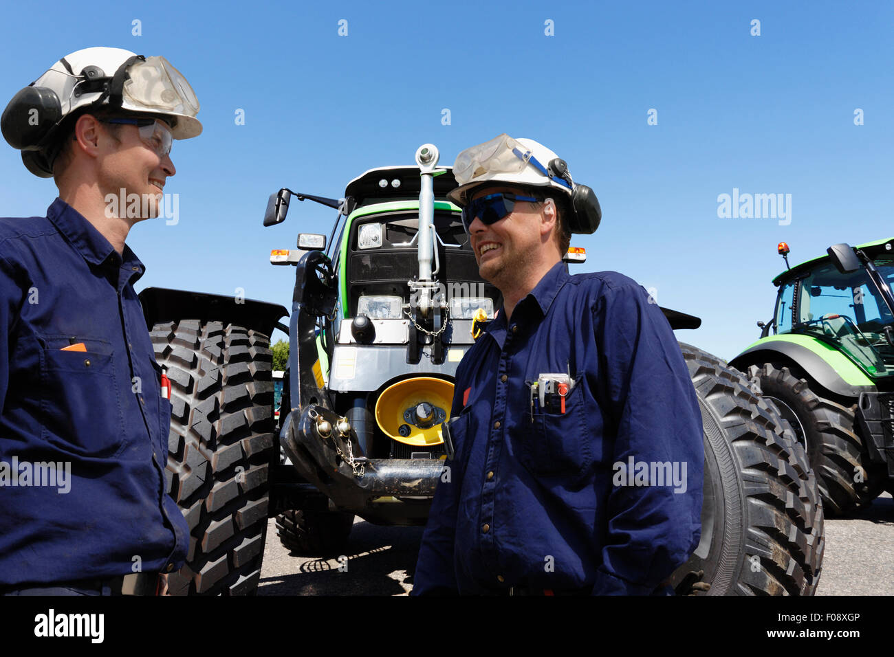 zwei Mechaniker mit riesigen landwirtschaftlichen Traktoren Stockfoto