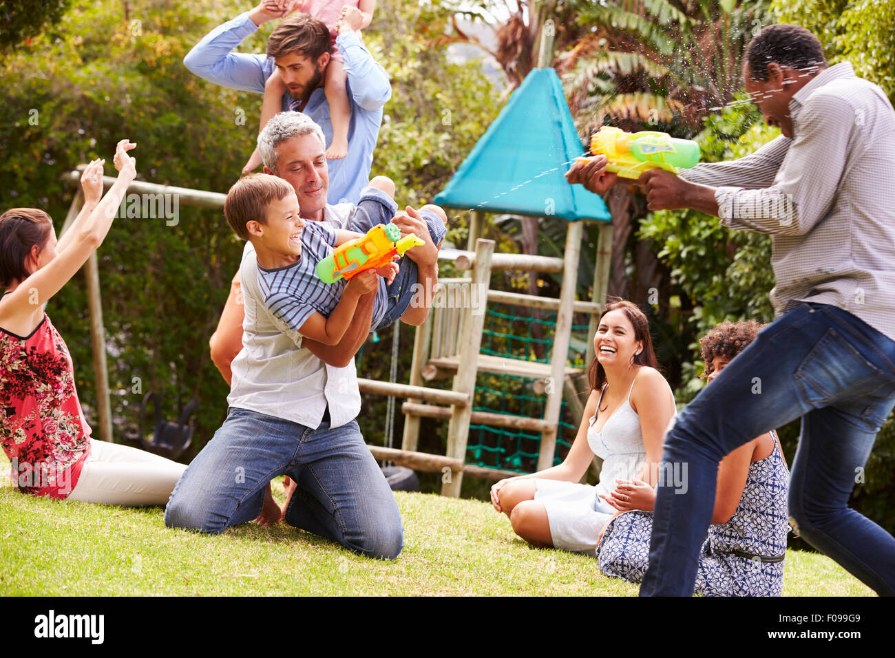 Erwachsene und Kinder Spaß mit Wasserpistolen in einem Garten Stockfoto