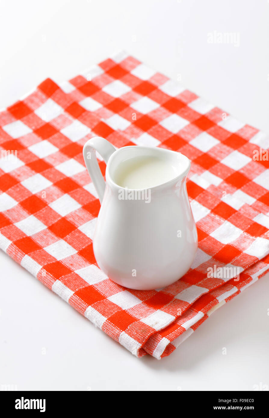 Krug mit Milch auf aufgegebenes Serviette Stockfoto