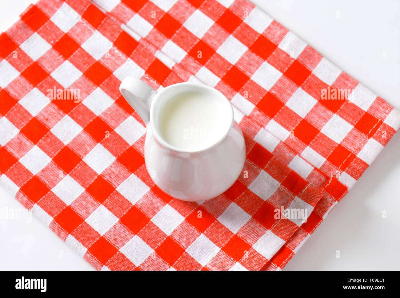 Krug mit Milch auf aufgegebenes Serviette Stockfoto