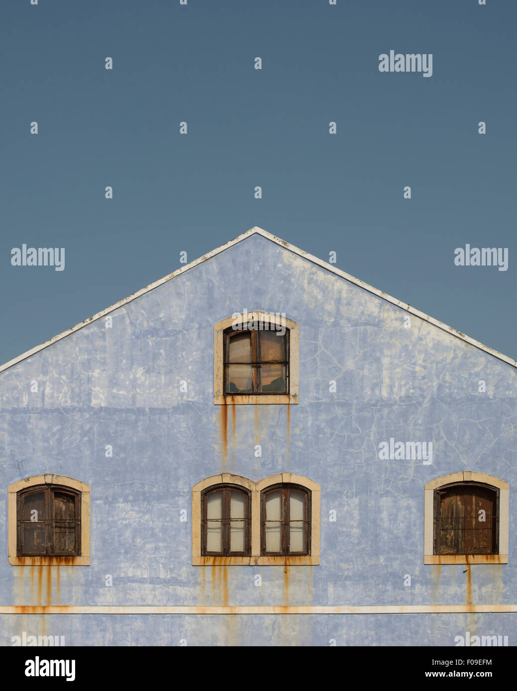 Weinende Haus. Die verwitterten blauen Wand waschen außerhalb eines Gebäudes kontrastiert mit der Korrosion von Eisen Flügelfenster laufen Stockfoto