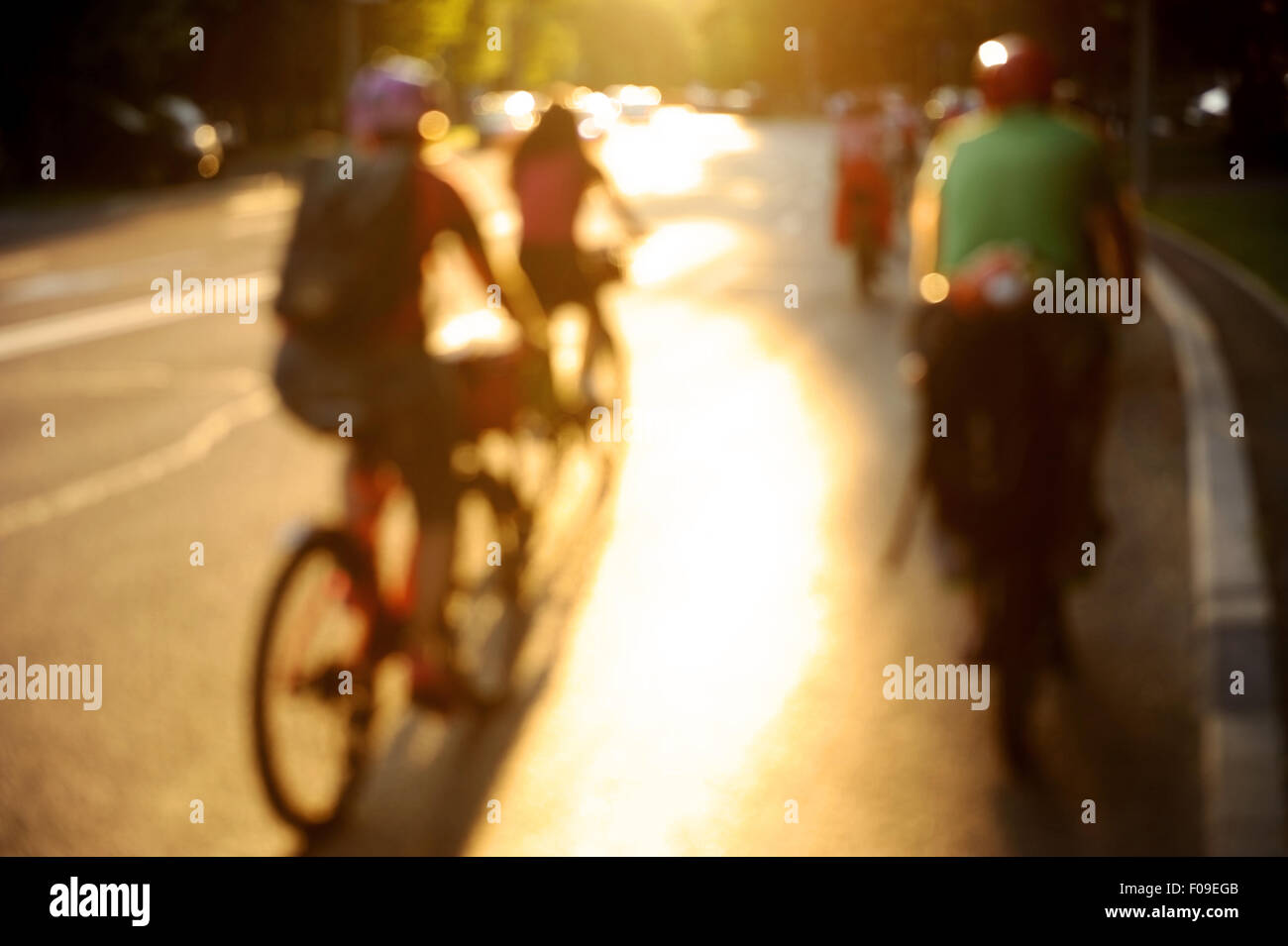 Unscharfes Foto von Frauen auf dem Fahrrad fahren in der Stadt bei Sonnenuntergang in schönes Licht Stockfoto