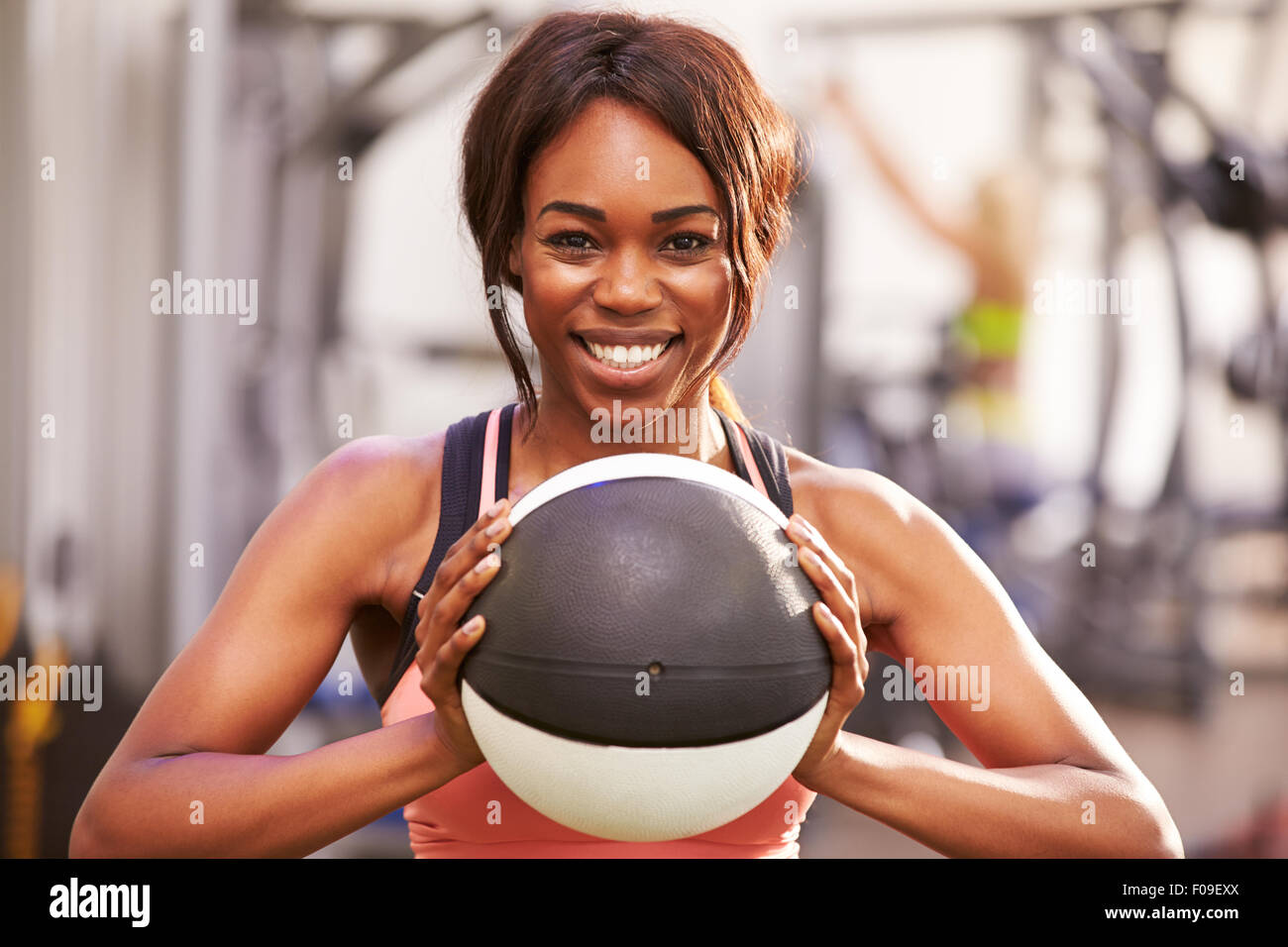 Porträt einer lächelnden Frau hält einen Medizinball in einem Fitnessstudio Stockfoto