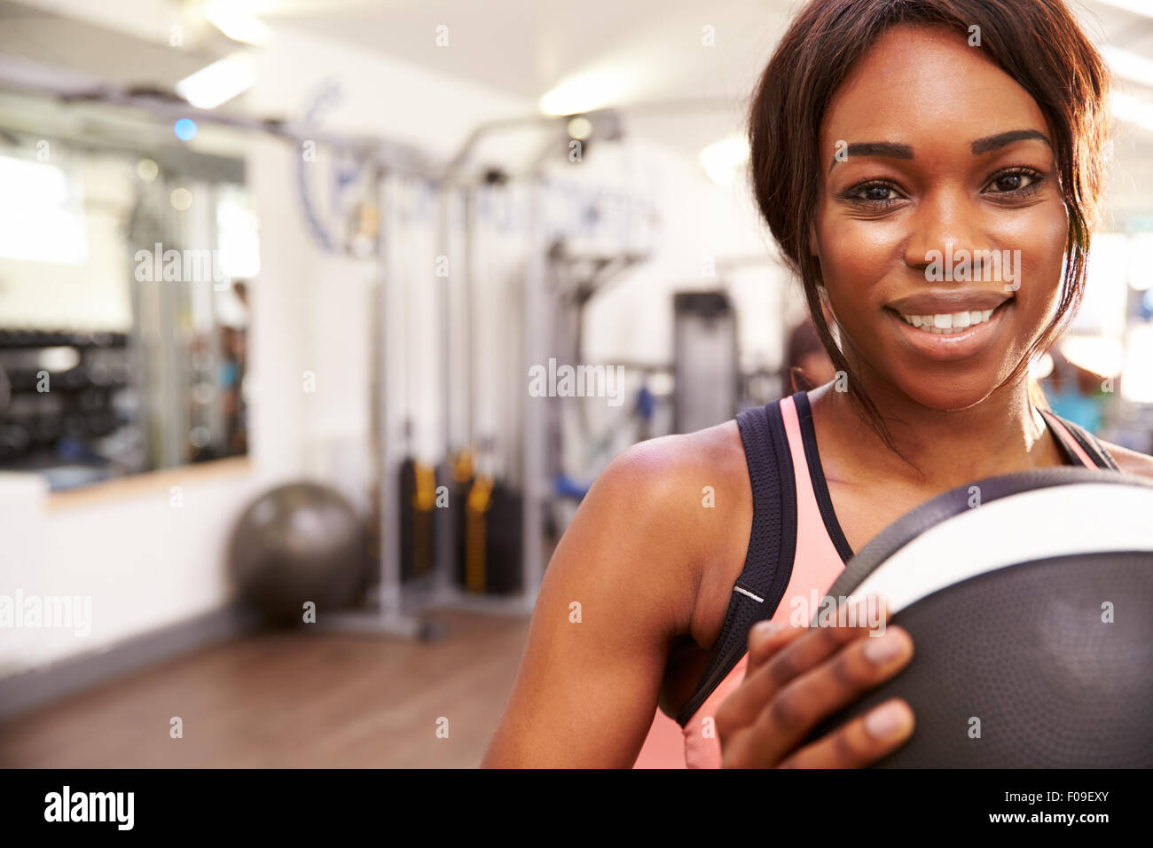 Porträt einer lächelnden Frau hält einen Medizinball in einem Fitnessstudio, Textfreiraum Stockfoto