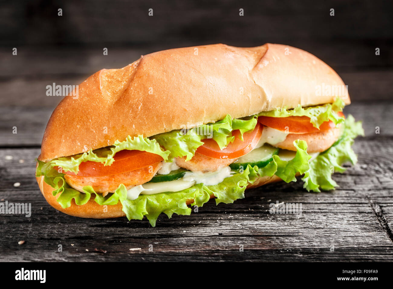 Sandwich mit Lachs Patty und Gemüse auf einem rustikalen Hintergrund Stockfoto