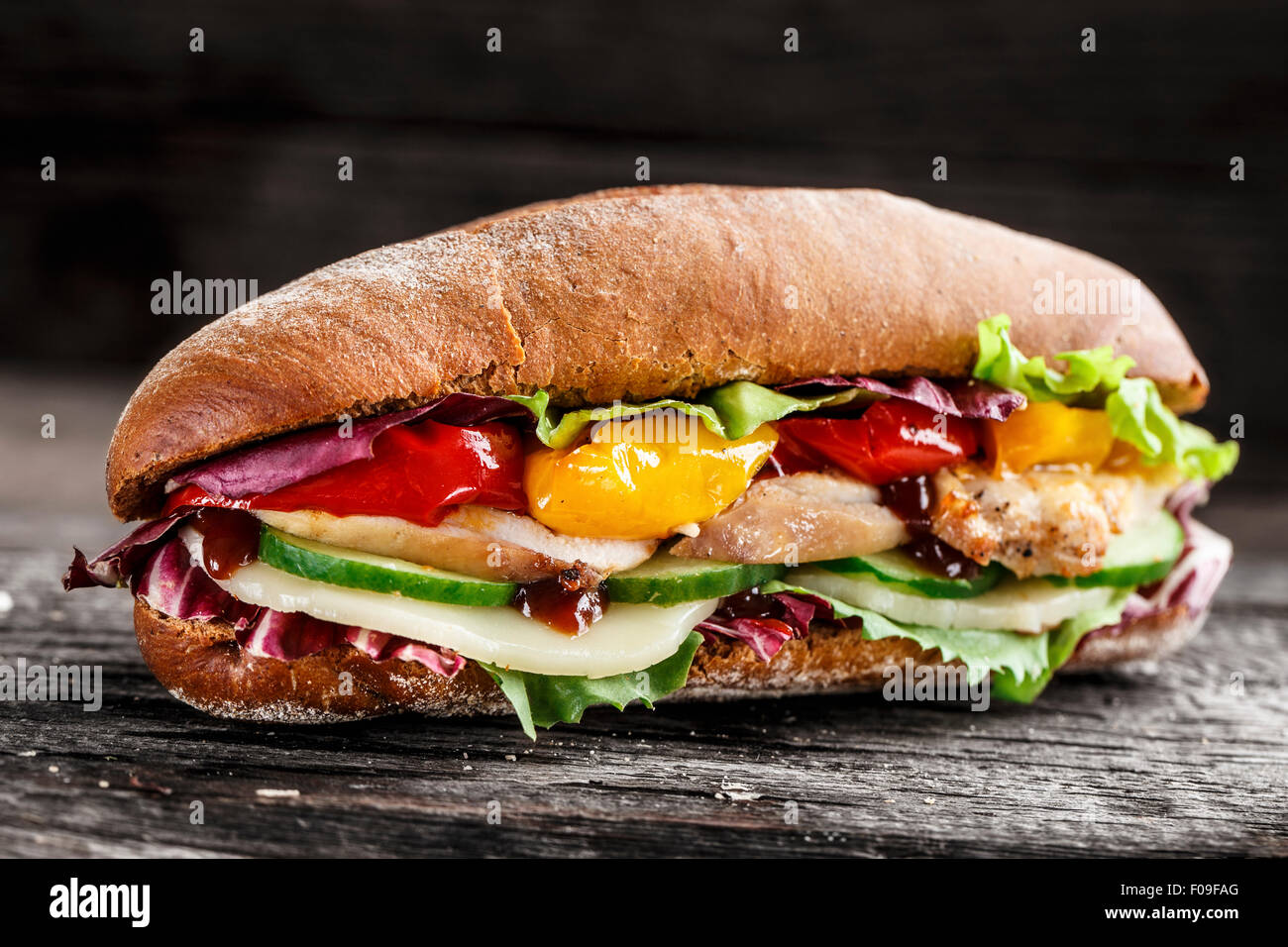 Sandwich mit Huhn, Käse und Gemüse auf einem rustikalen Hintergrund Stockfoto