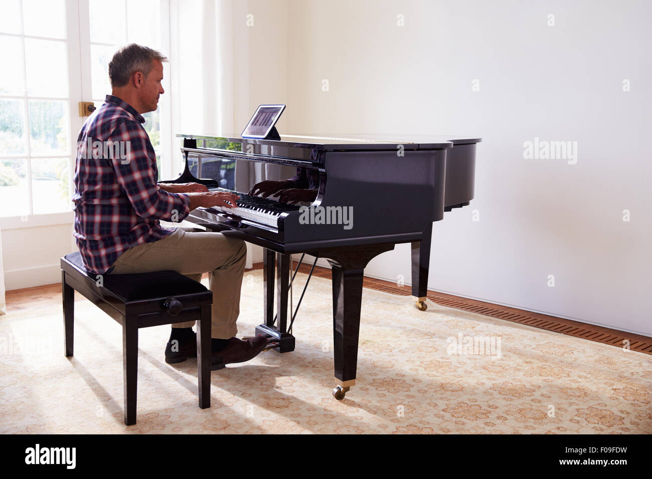 Mann mit Digital-Tablette Anwendung Klavierspielen lernen Stockfoto