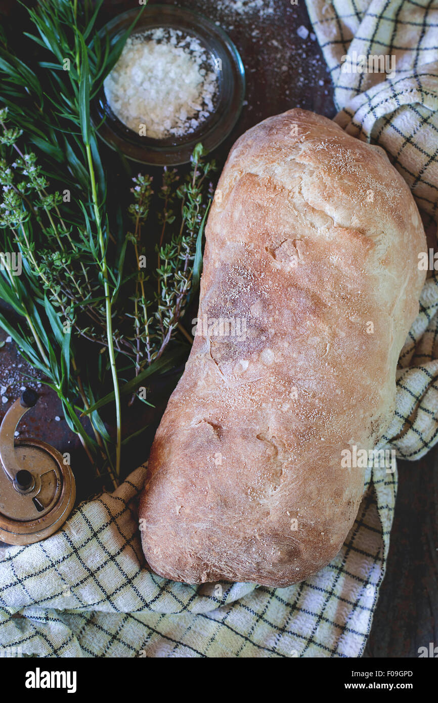 Frisch gebackenes Ciabatta-Brot mit Salz und Kräutern Thym und Oregano. Weiß kontrolliert Küchentuch über Metall Hintergrund. Natürliches d Stockfoto