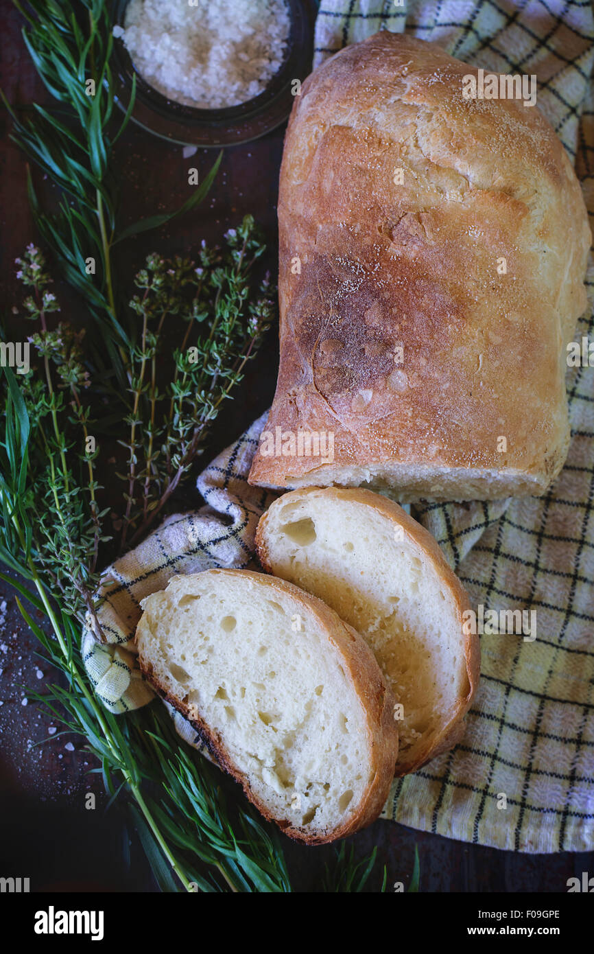 In Scheiben frisch gebackenes Ciabatta Brot mit Salz und Kräutern Thym und Oregano. Weiß kontrolliert Küchentuch über Metall Hintergrund. Na Stockfoto