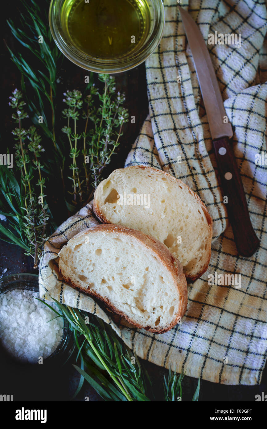 In Scheiben frisch gebackenes Ciabatta Brot mit Salz, Oregano, Olivenöl und Kräutern Thym. Auf weißen überprüft Küchentuch mit Messer ove Stockfoto