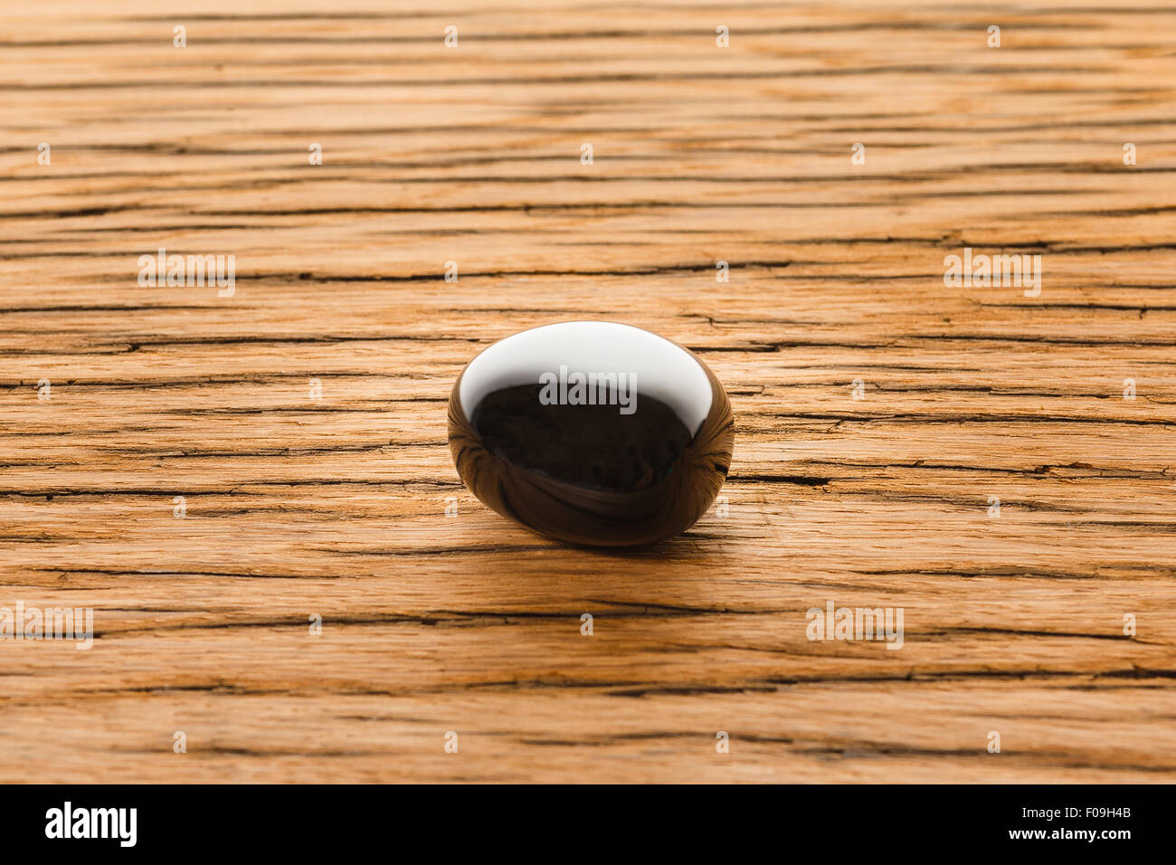 Obsidian auf Eiche Holzoberfläche. Magmatischen Juwel Stein hochglänzend. Stockfoto