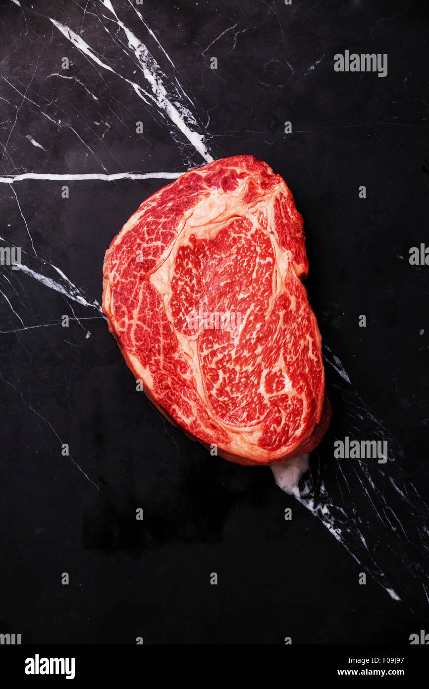 Rohe marmorierte Frischfleisch Black Angus Steak Ribeye auf schwarzem Marmor Hintergrund Stockfoto