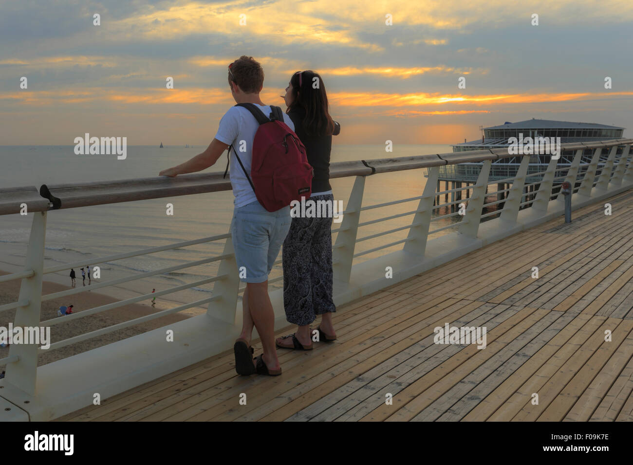 Paar genießt die Aussicht auf den Sonnenuntergang vom Scheveningen Pier auf dem Oberdeck, den Haag (Den Haag), Süd-Holland, Niederlande. Stockfoto