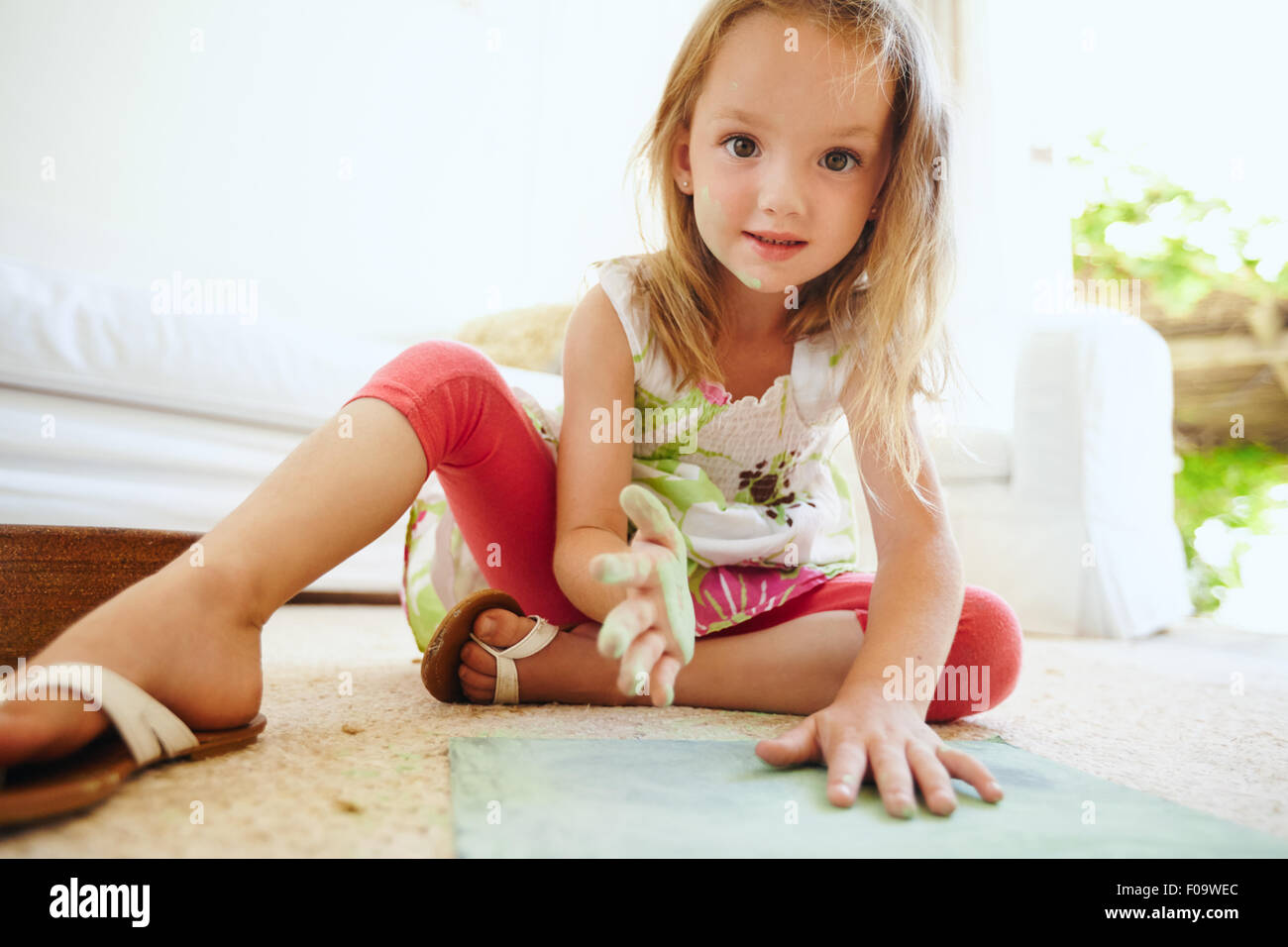 Porträt der schönen kleines Schulmädchen Färbung ein Bild. Mädchens Hand gemalt mit grüner Kreide Farbe Blick in die Kamera. Stockfoto