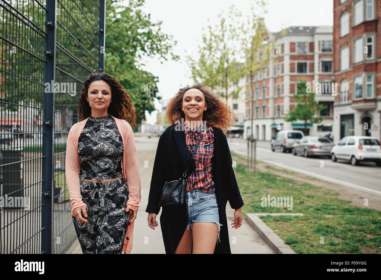 Im Freien Schuss von zwei Freundinnen, die zu Fuß durch die Stadt. Glückliche junge Frauen zusammen spazieren entlang einer Stadtstraße. Stockfoto