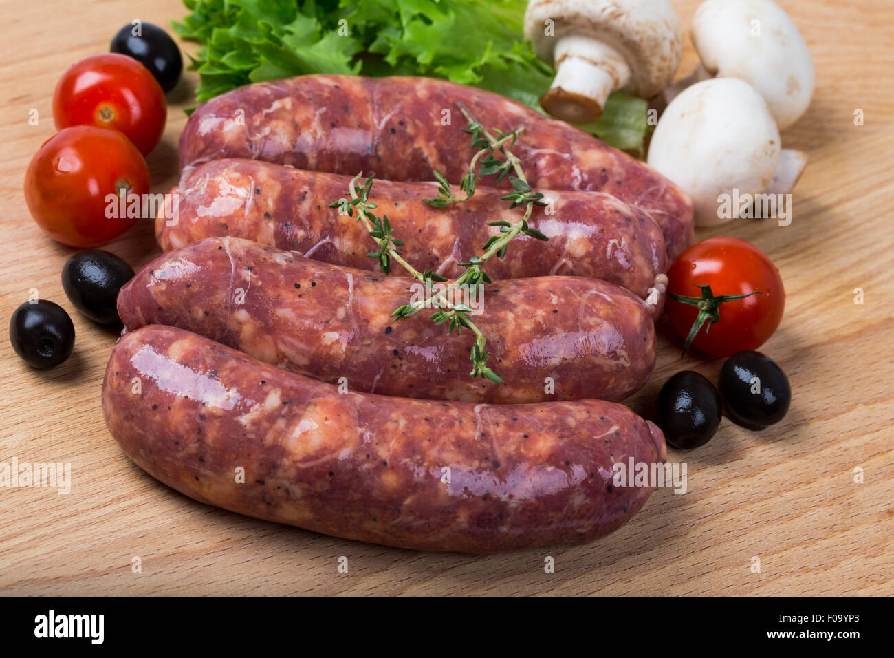 ungekocht Rohwürste mit Salat, Tomaten, Pilze auf Holzbrett Stockfoto