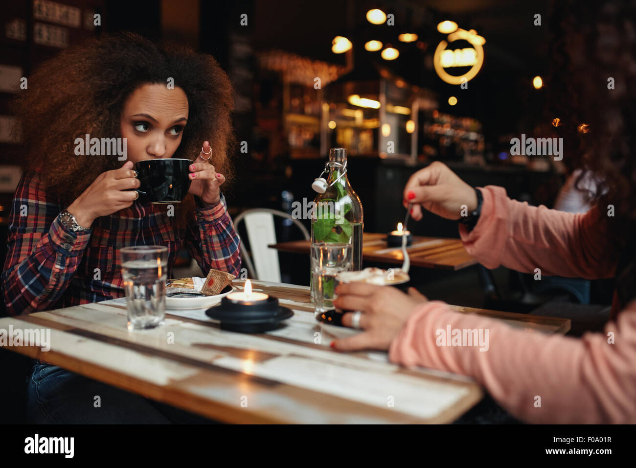 Junge Frau Kaffee trinken. Afrikanische Mädchen sitzen im Café mit Kaffee und wegsehen. Stockfoto