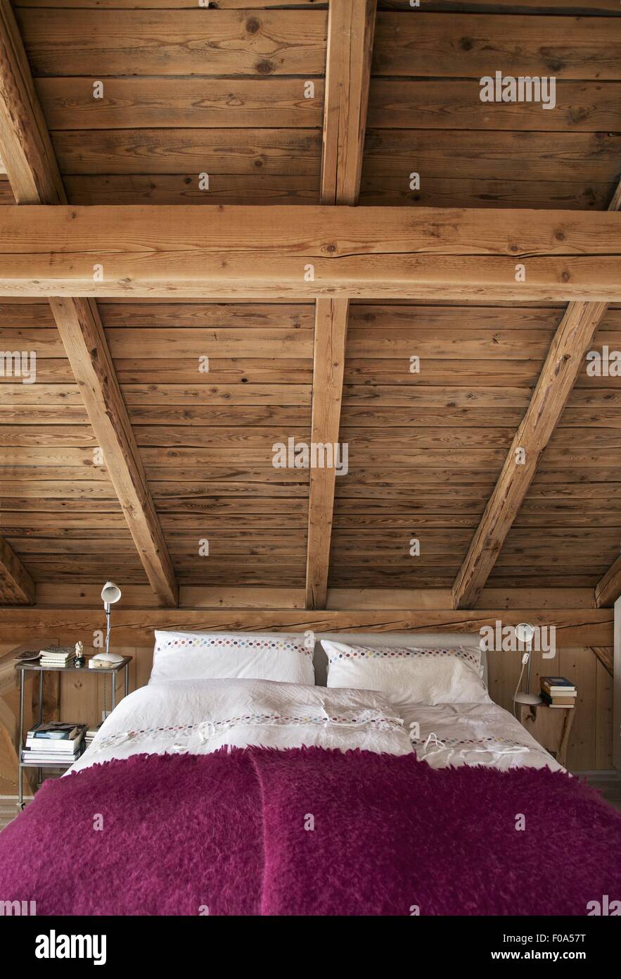 Schlafzimmer mit Bett unter Holzdecke Stockfoto