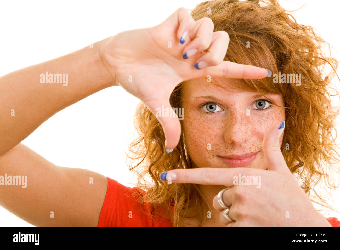 Junge rothaarige Frau, die durch Finger-Rahmen Stockfoto