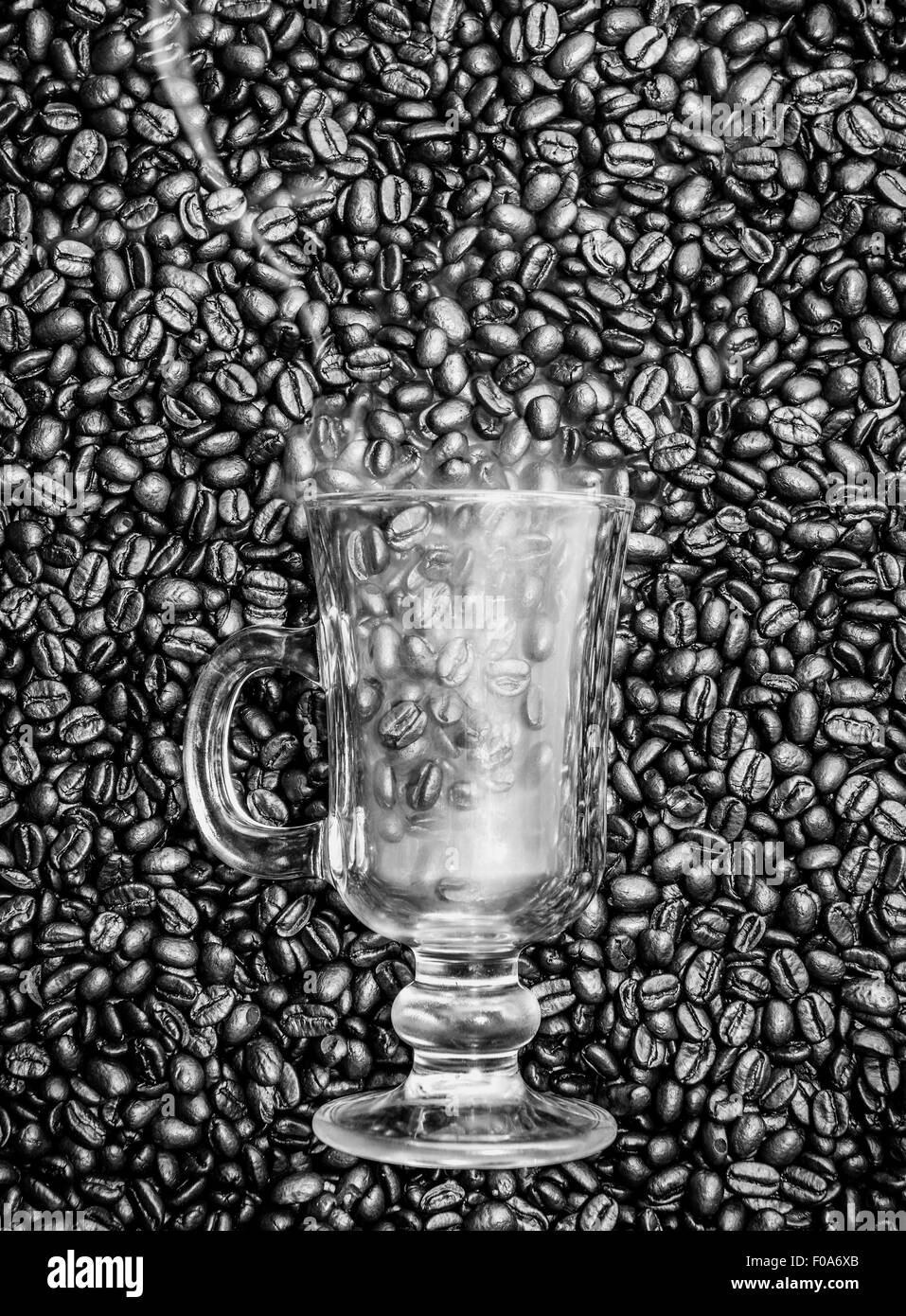 Irish Coffee Glas stecken in frischen Kaffeebohnen. Rauch kommt aus dem Glas. Stockfoto