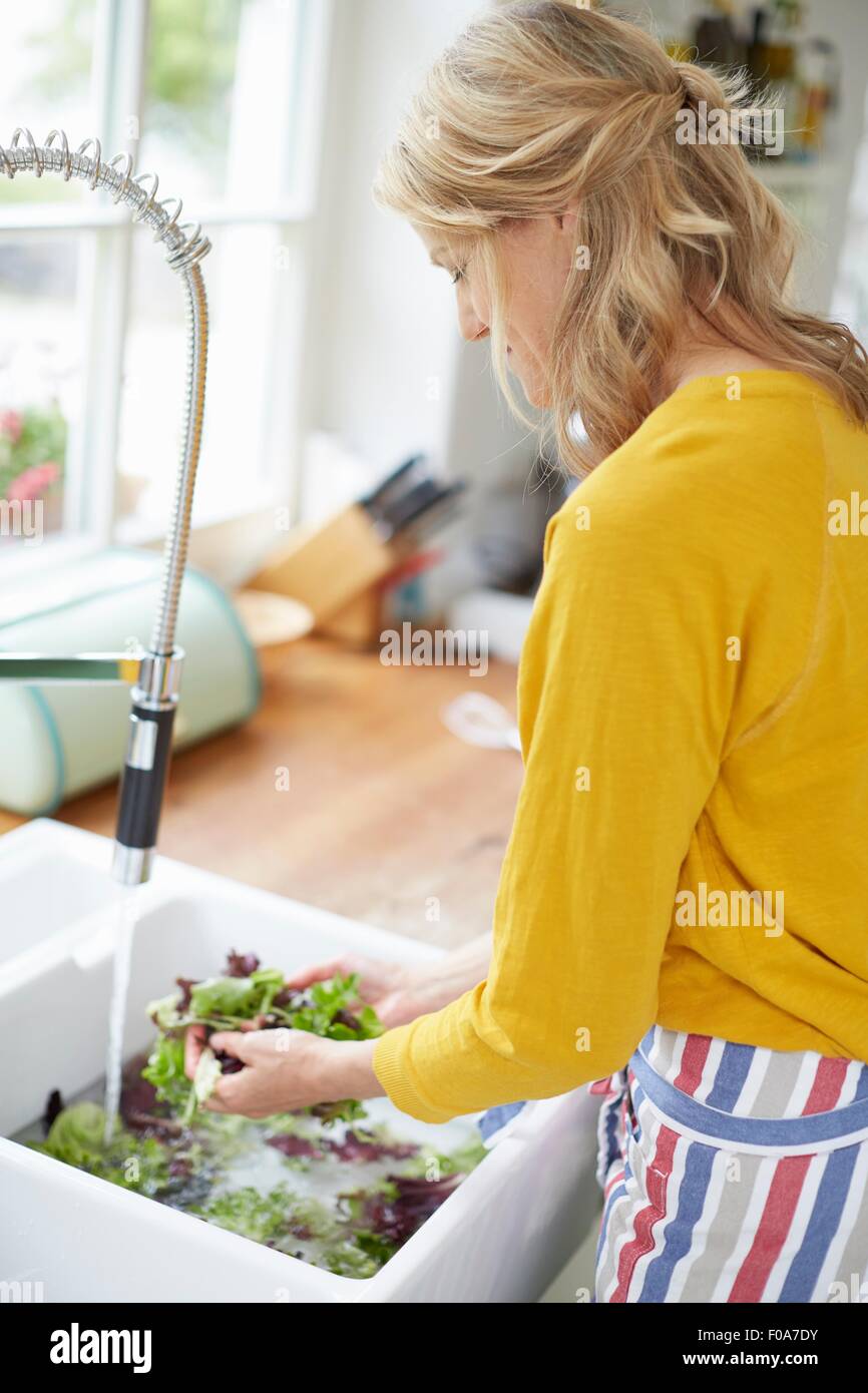 Waschen Sie Gemüse in Küchenspüle Frau Stockfoto