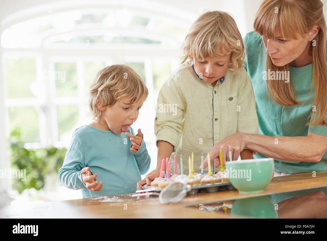Mutter und Söhne machen Cupcakes in Küche Stockfoto