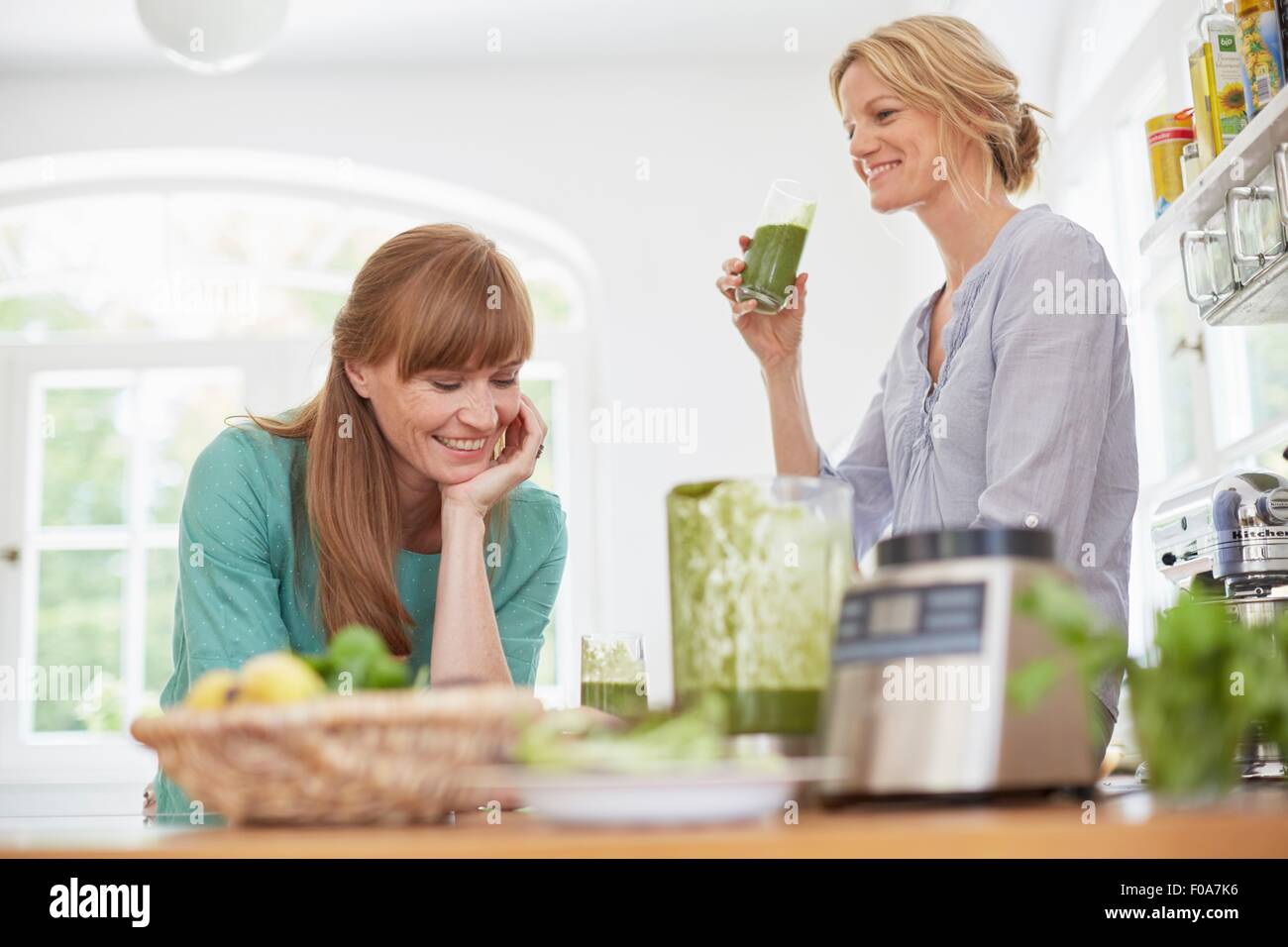 Frauen trinken grünen veganen Smoothie in Küche Stockfoto