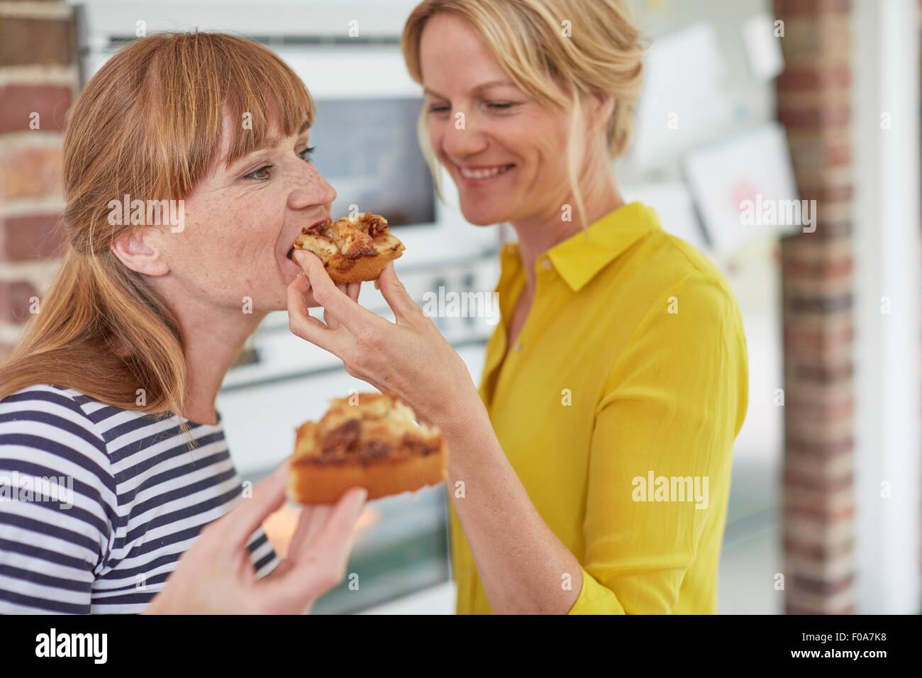 Frauen essen Kuchen in Küche Stockfoto