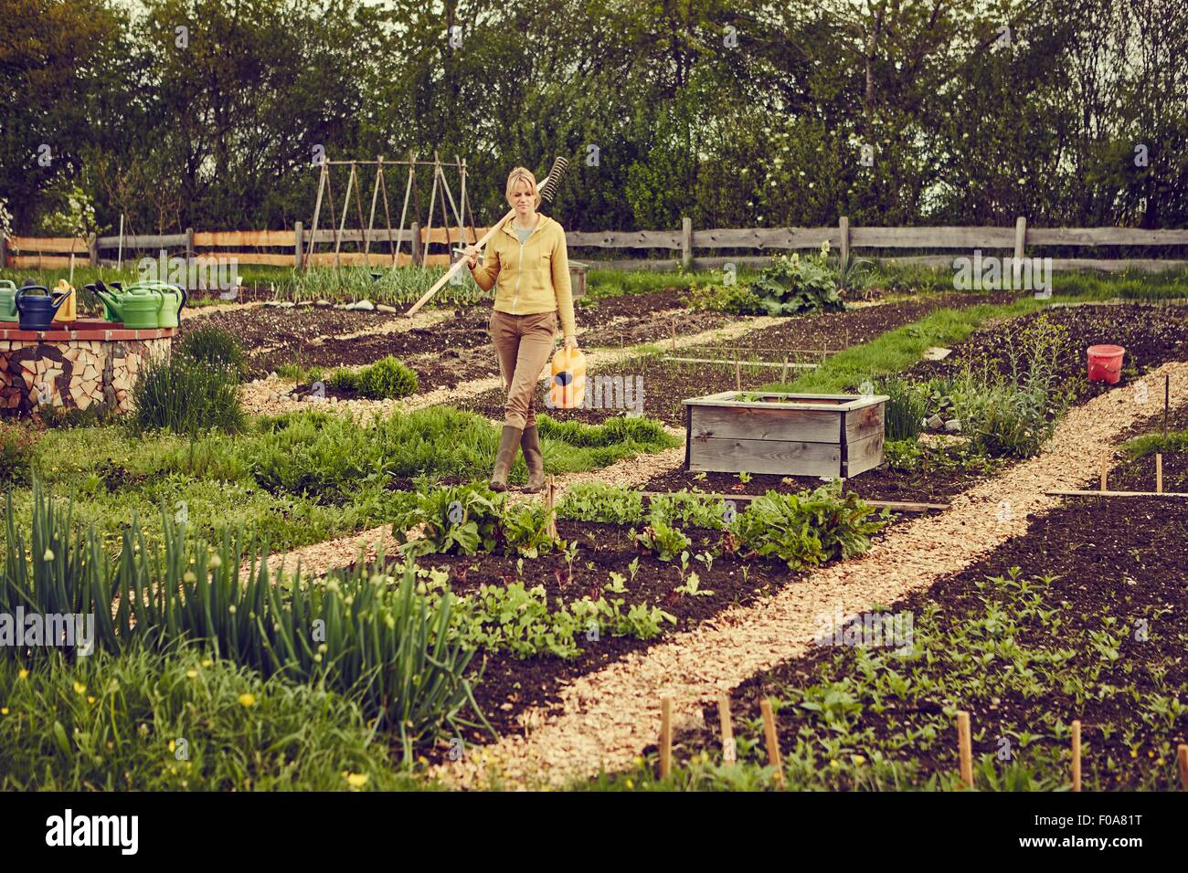 Reife Frau, Gartenarbeit, mit Rechen und Gießkanne Stockfoto