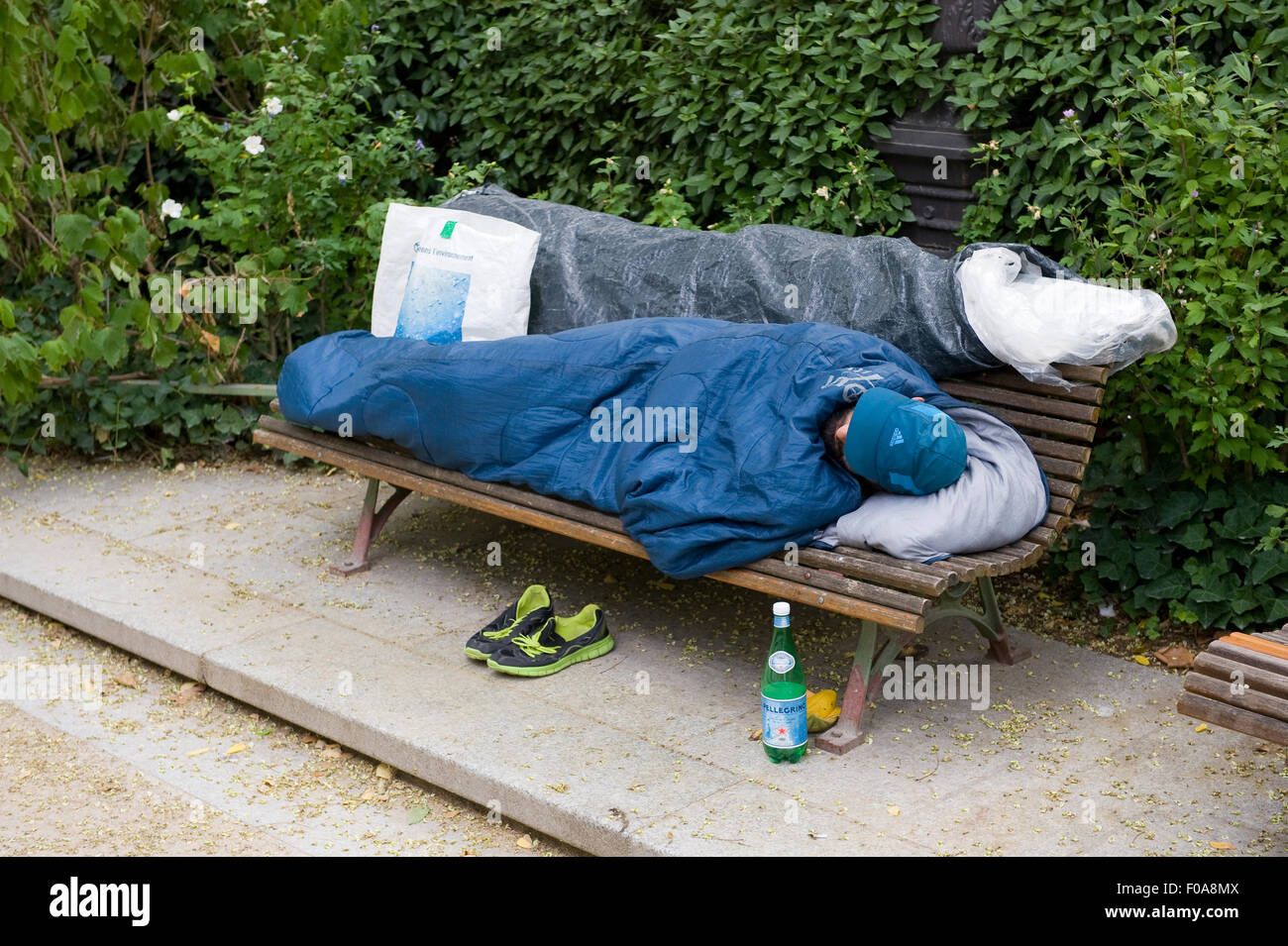 PARIS, Frankreich - 27. Juli 2015: Ein Obdachloser auf einer Bank in einem Park in Paris in Frankreich schläft Stockfoto