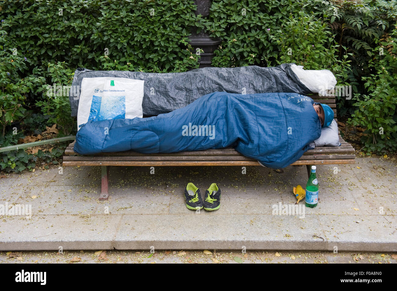 PARIS, Frankreich - 27. Juli 2015: Ein Obdachloser auf einer Bank in einem Park in Paris in Frankreich schläft Stockfoto