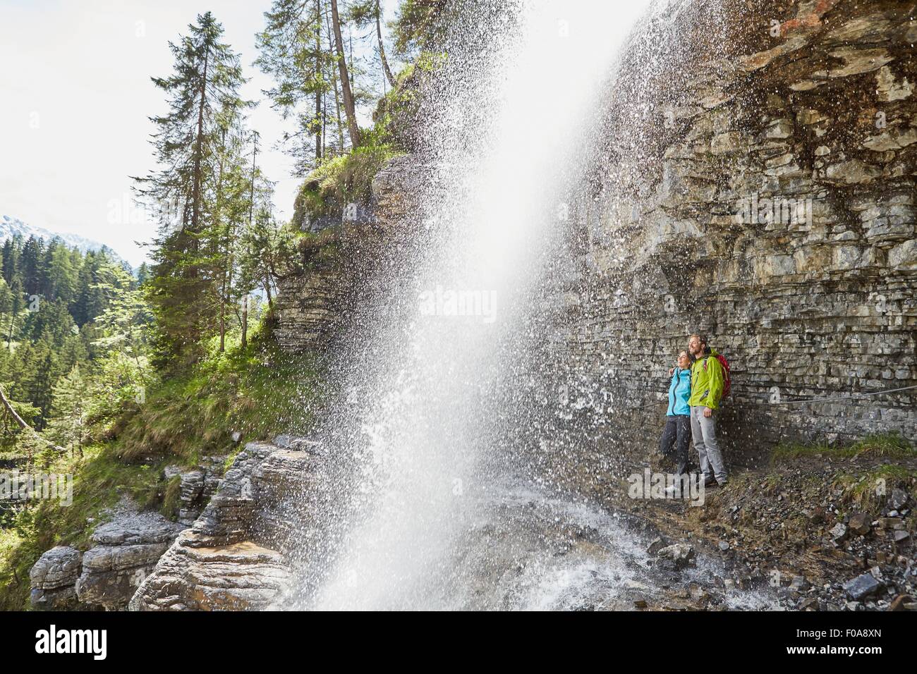 Junges Paar stehen unter Wasserfall, auf der Suche, Tirol, Österreich Stockfoto