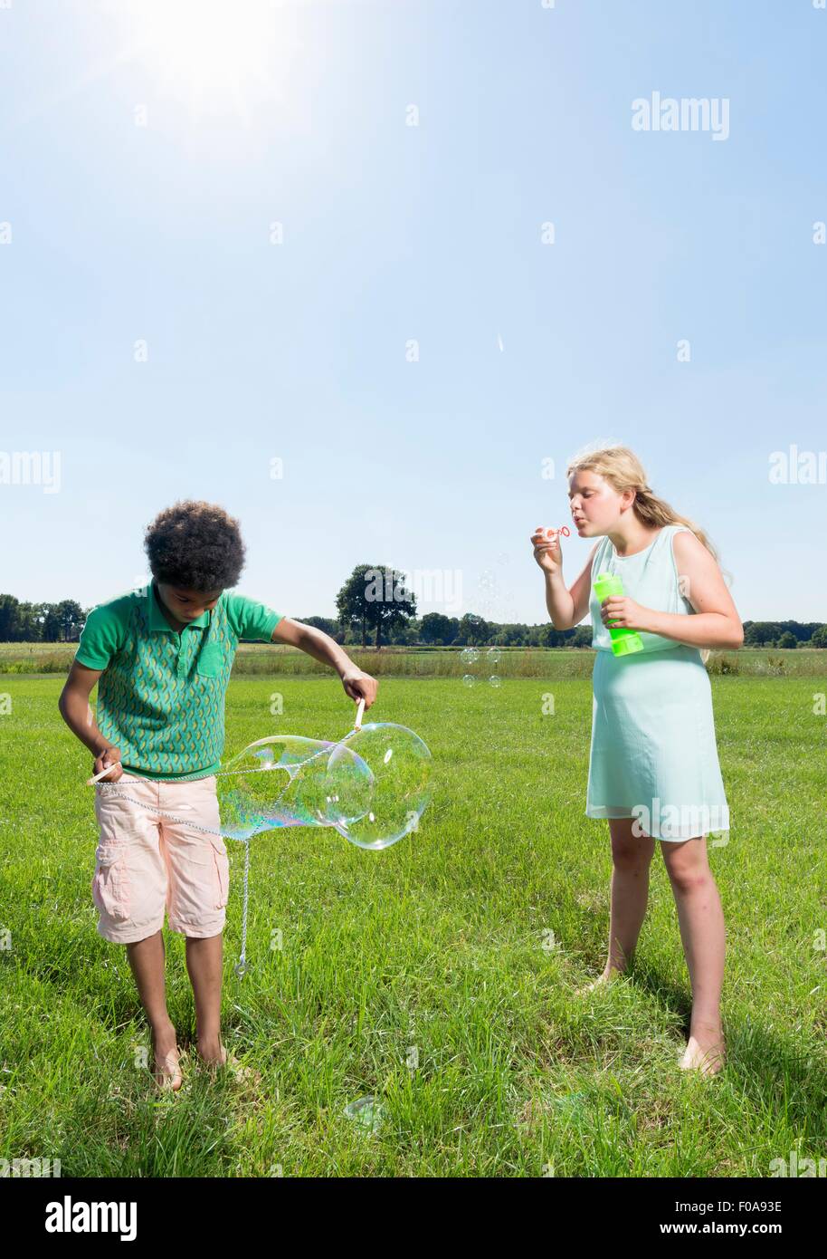 Jungen und Mädchen bläst Seifenblasen im Feld Stockfoto