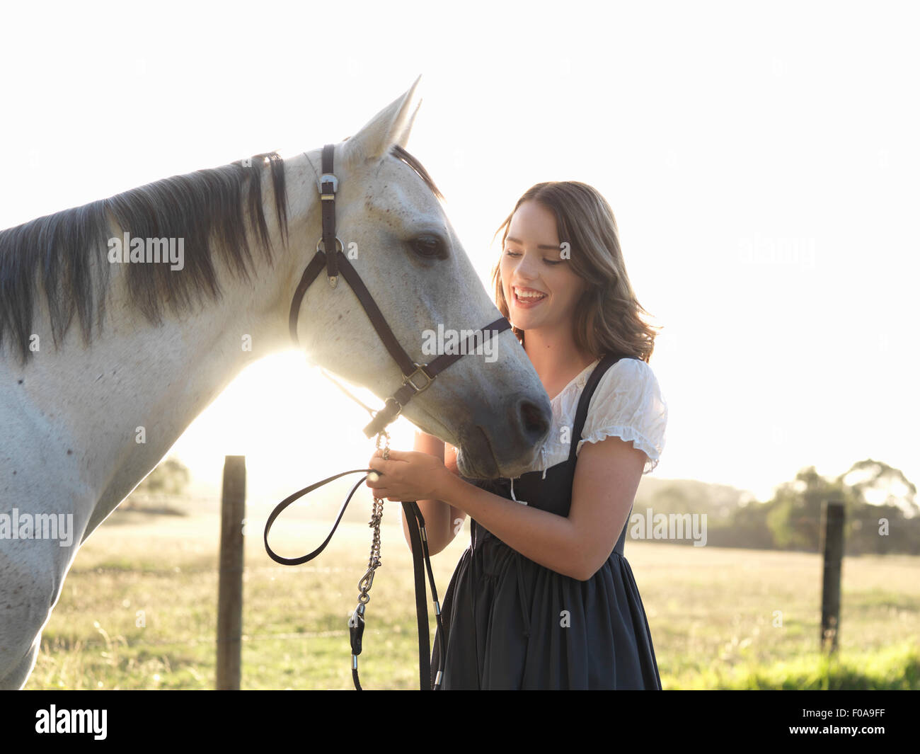 Porträt von Teenager-Mädchen und ihr grau Pferd im sonnigen Feld Stockfoto