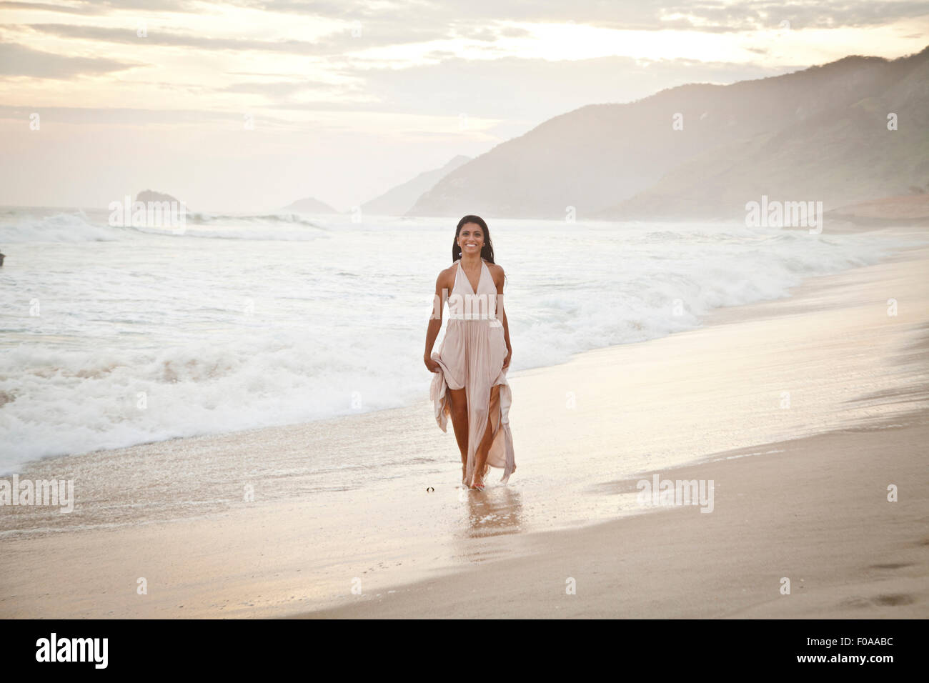 Mitte der erwachsenen Frau am Strand entlang zu laufen Stockfoto