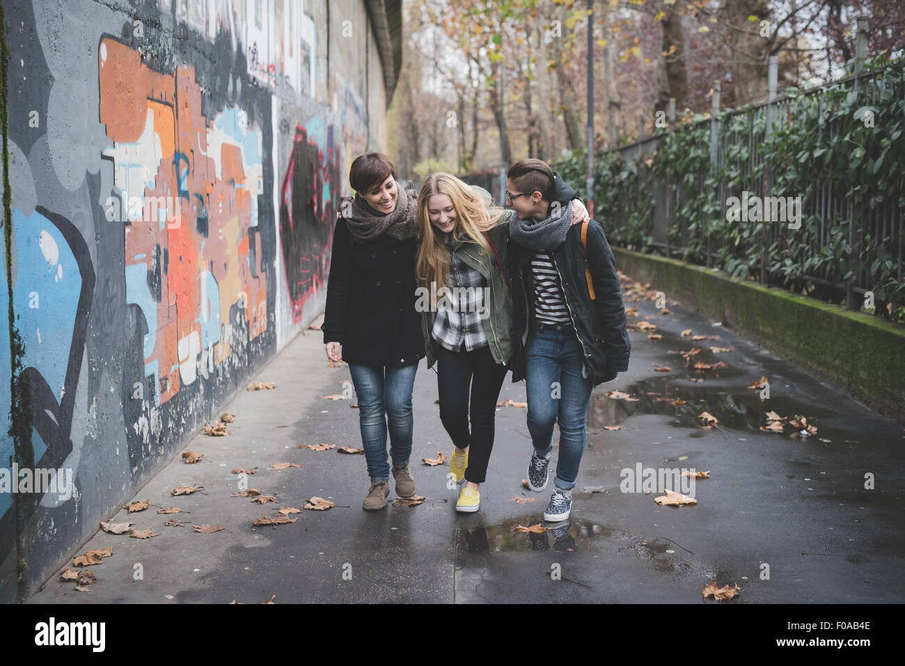 Drei Schwestern, die zu Fuß durch Graffitiwand Stockfoto