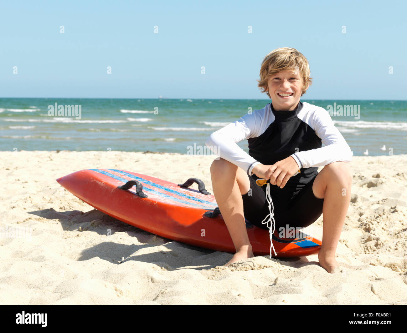 Porträt von überzeugt junge Nipper (Kind Surf Life Savers) sitzen auf Surfbrett am Strand, Altona, Melbourne, Australien Stockfoto