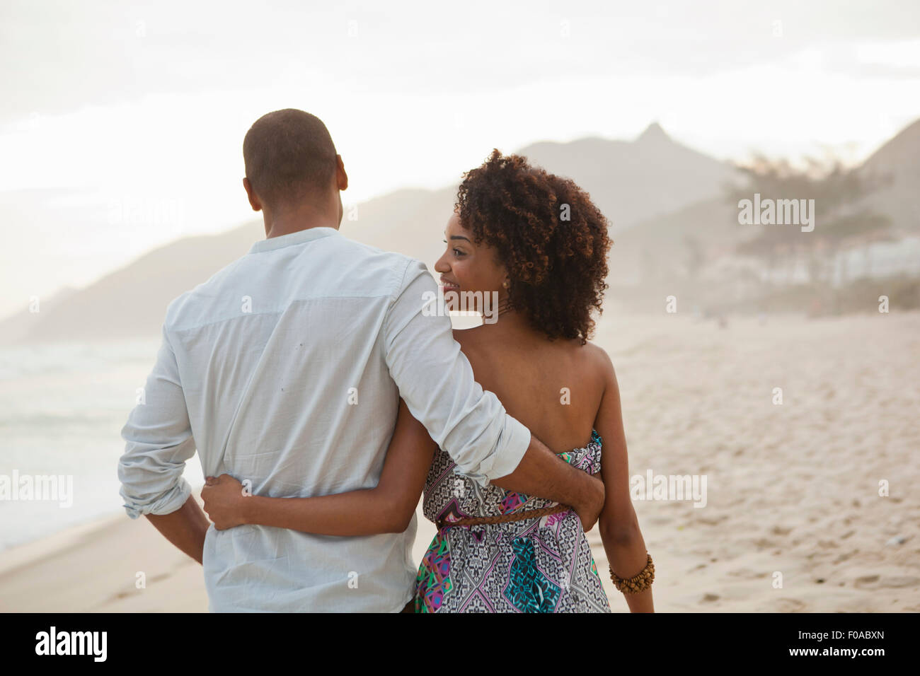 Junge Frau auf der Suche über die Schulter mit Freund beim Spaziergang am Strand, Rio De Janeiro, Brasilien Stockfoto