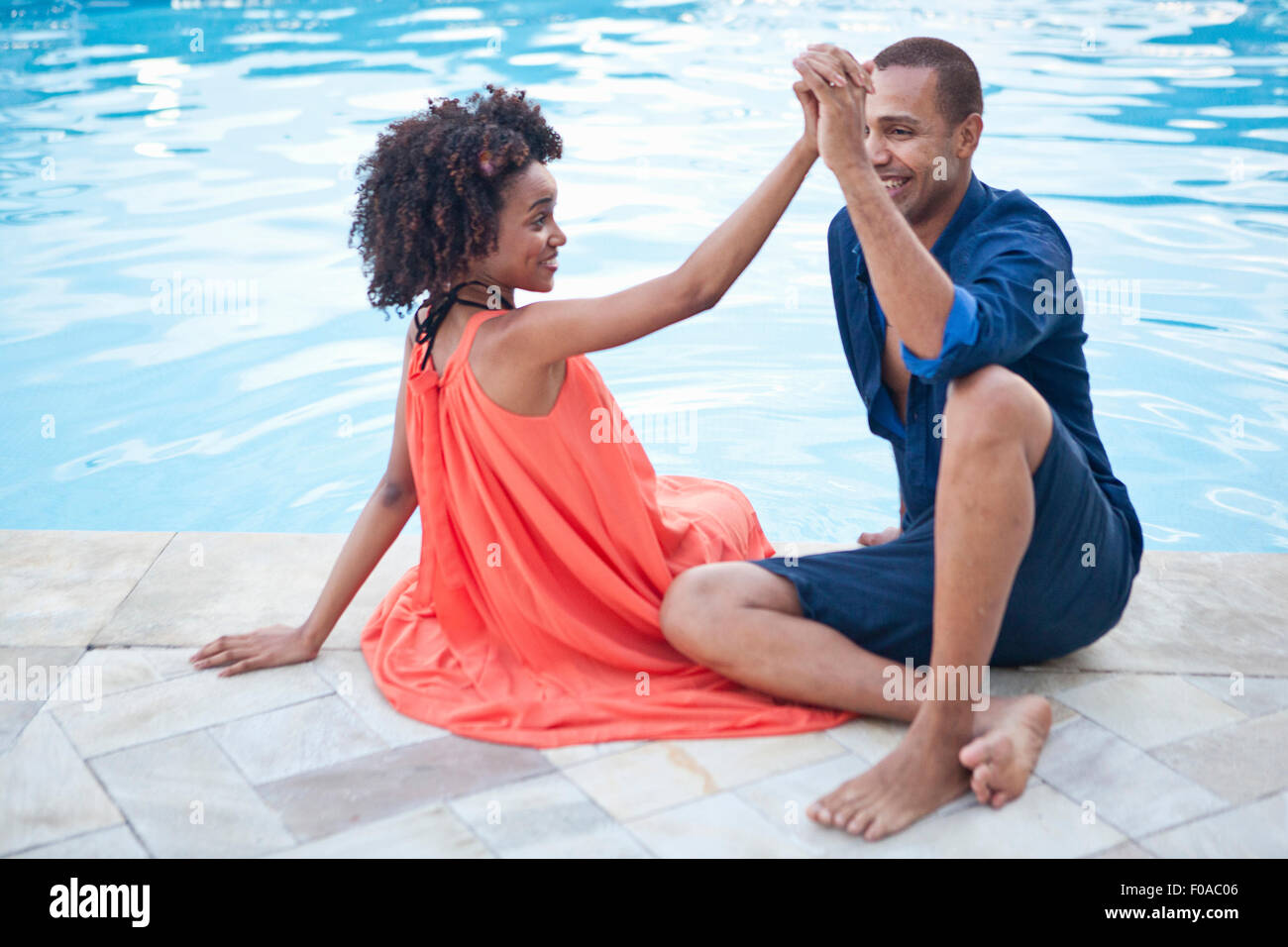 Stilvolle paar sitzen Hand in Hand am Hotel Pool, Rio De Janeiro, Brasilien Stockfoto