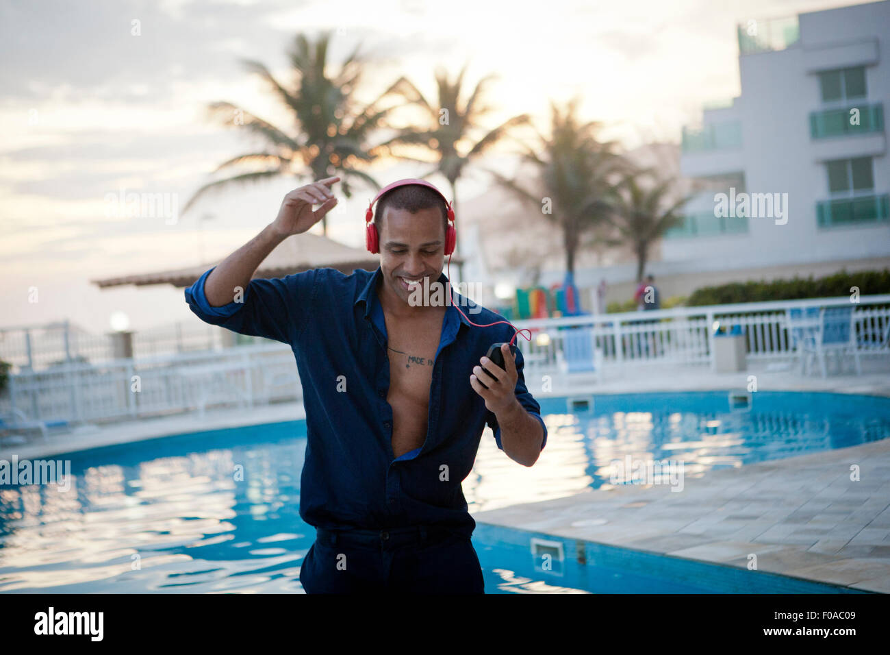 Mitte erwachsener Mann tanzen zu Smartphone Musik am Hotel Pool, Rio De Janeiro, Brasilien Stockfoto